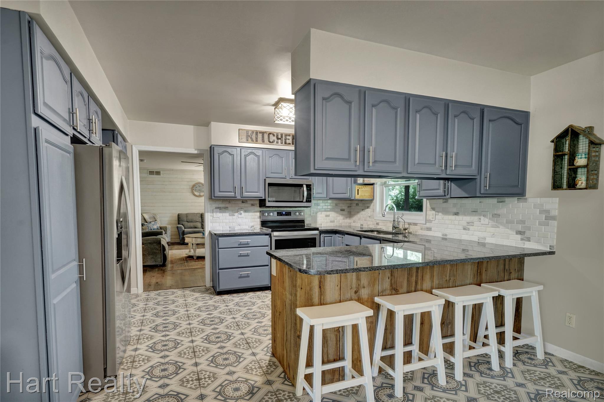 7167 Brown School Road North Branch, MI 48461 - Photo 19 of 51 Kitchen featuring blue cabinetry with silver hardware, patterned floor tiling, and a breakfast bar with wood-finish paneling