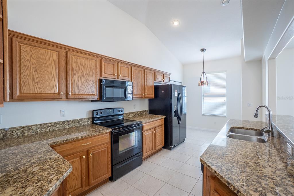 107 Raintree Circle Palm Coast, FL 32164 - Photo 11 of 46 a kitchen with stainless steel appliances granite countertop a sink stove microwave and refrigerator