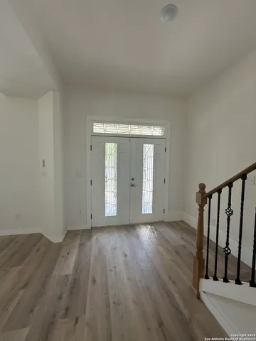 a view of an empty room with wooden floor and window