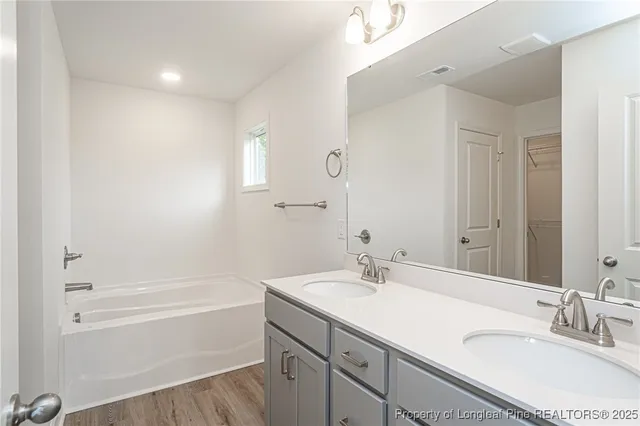a bathroom with a tub sink double vanity granite tub and shower