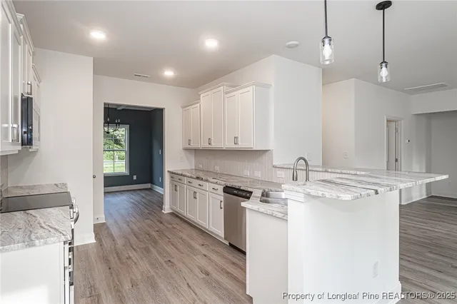 a kitchen with stainless steel appliances granite countertop a sink a stove and a wooden floors