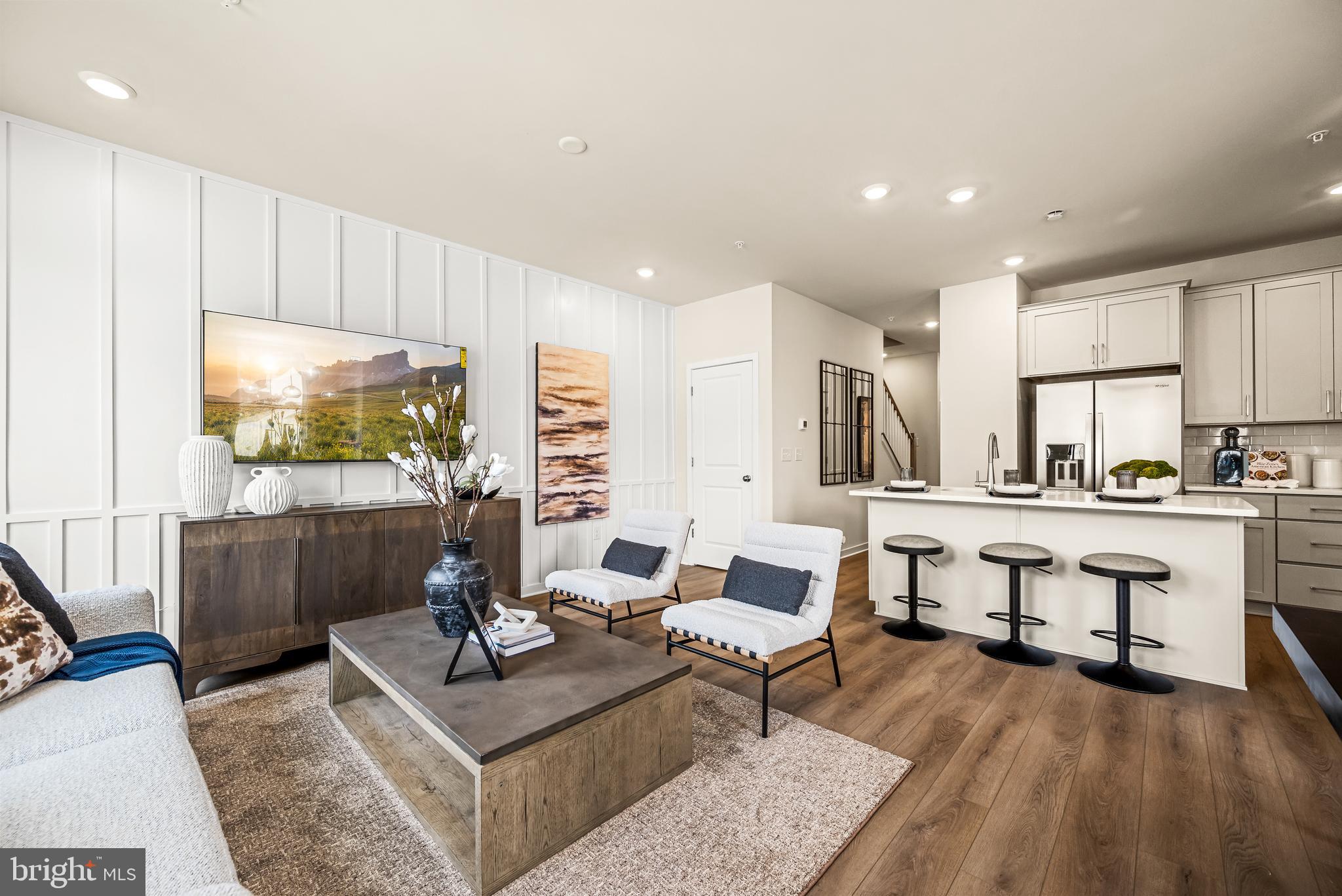 a living room with furniture a flat screen tv and kitchen view