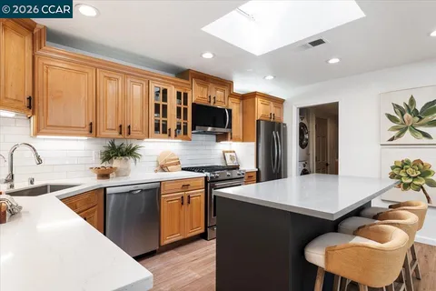 a large kitchen with stainless steel appliances granite countertop a sink a stove and refrigerator