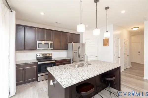 a kitchen with stainless steel appliances granite countertop a sink a refrigerator and a stove