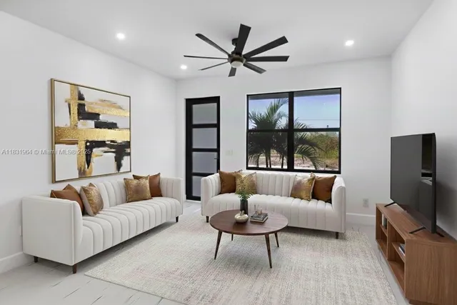 a living room with furniture a ceiling fan a flat screen tv and a large window