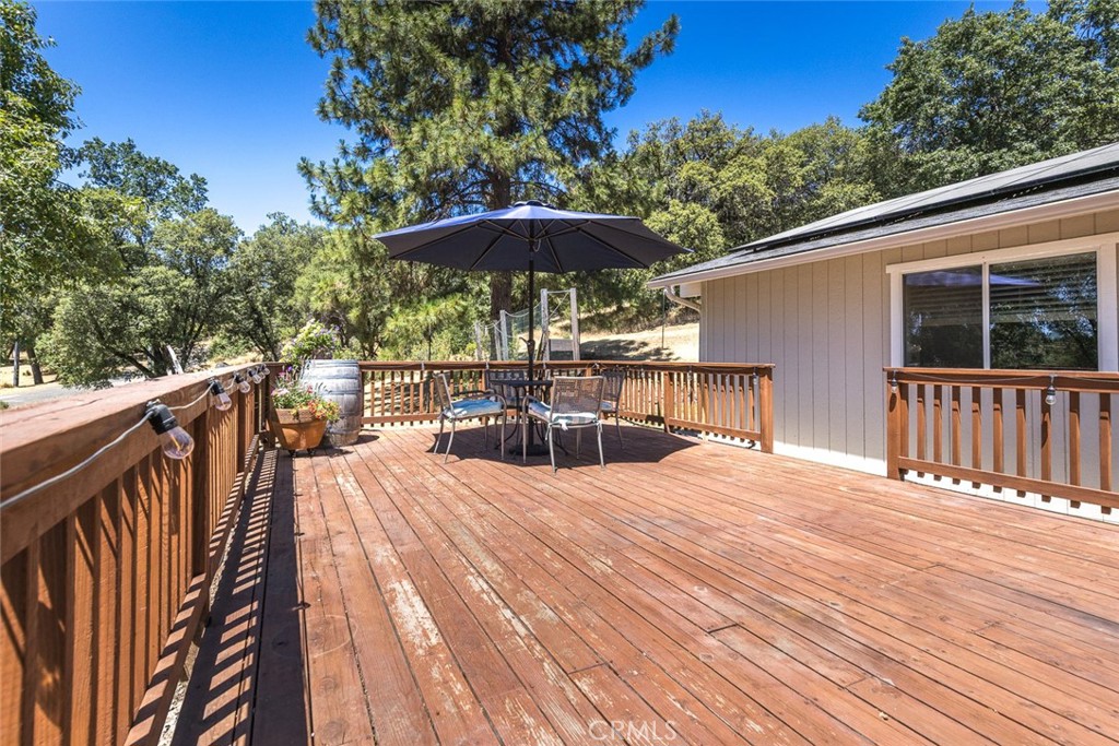 45315 Forest Ridge Drive Ahwahnee, CA 93601 - Photo 33 of 75 a view of a roof deck with table and chairs under an umbrella with wooden floor and fence