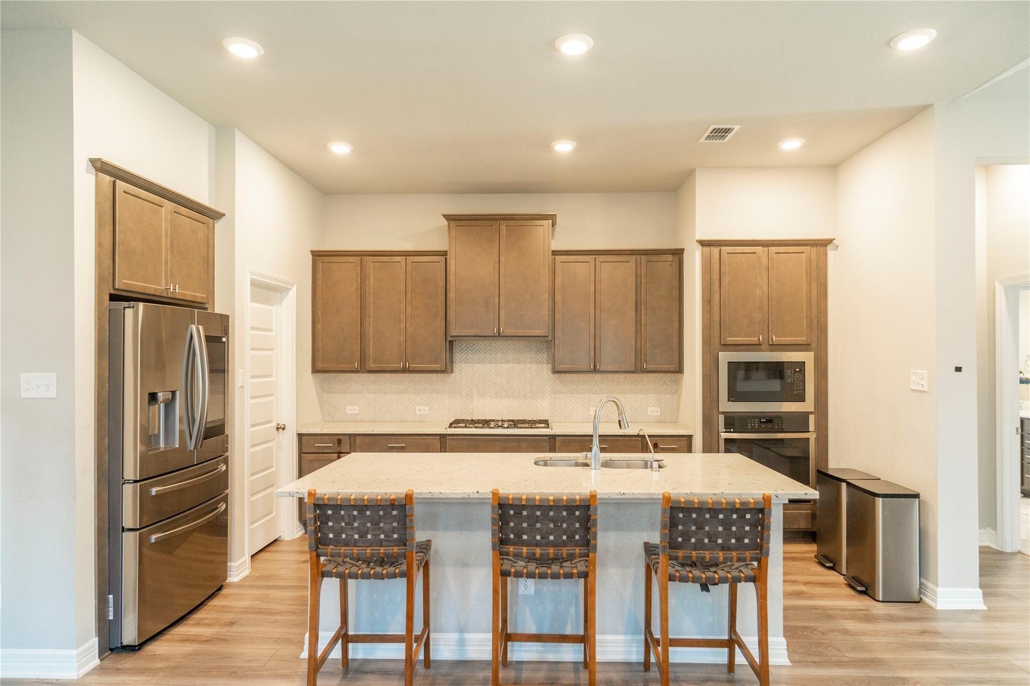 29023 Laurel Grove Lane Fulshear, TX 77441 - Photo 12 of 42 a kitchen with kitchen island granite countertop a refrigerator and a stove top oven
