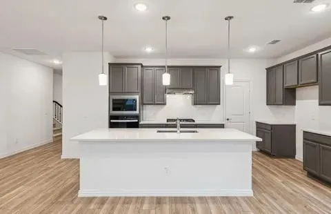 a large kitchen with kitchen island a large counter top a stove a sink and a center island