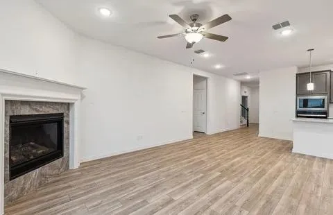 a view of an empty room with kitchen and a fireplace