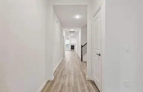 a view of a hallway with wooden floor and a bathroom