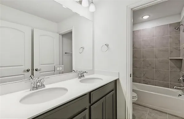 a bathroom with a sink double vanity granite tub shower and a mirror