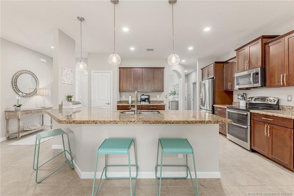 2185 Northwest Dalea Way Stuart, FL 34994 - Photo 14 of 55 a large kitchen with kitchen island granite countertop a stove a sink a oven a dining table and chairs