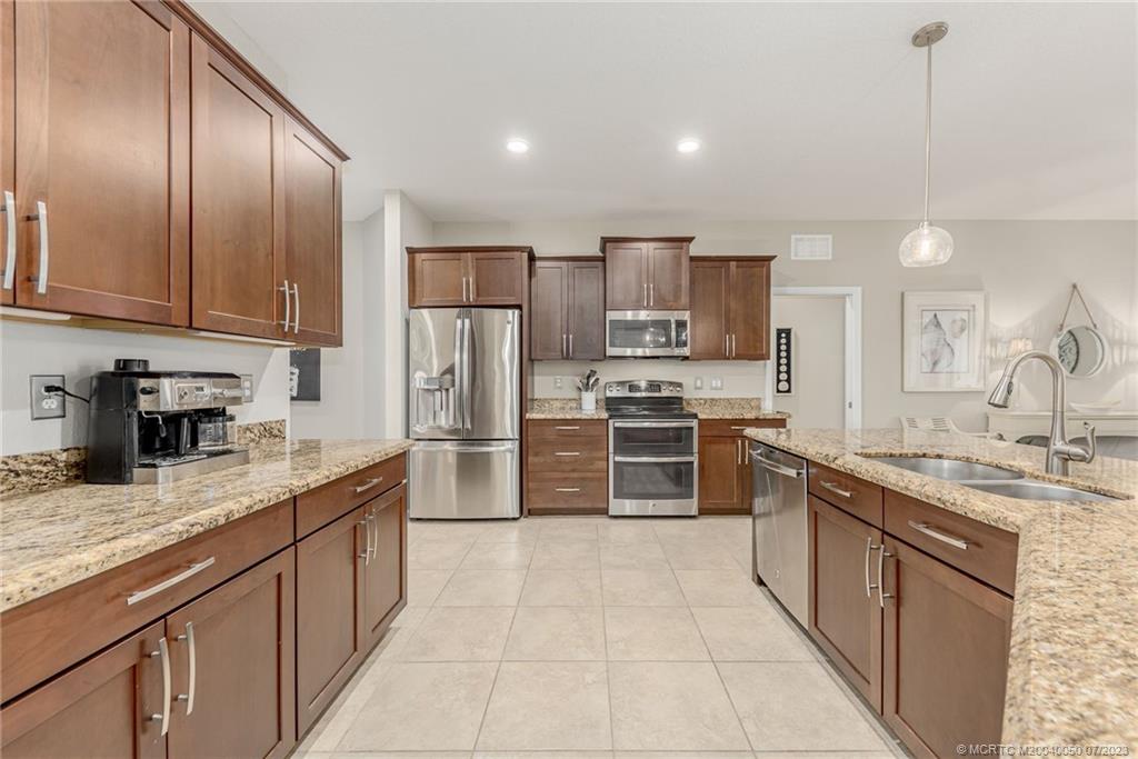 2185 Northwest Dalea Way Stuart, FL 34994 - Photo 16 of 55 a kitchen with stainless steel appliances granite countertop a sink stove refrigerator and cabinets