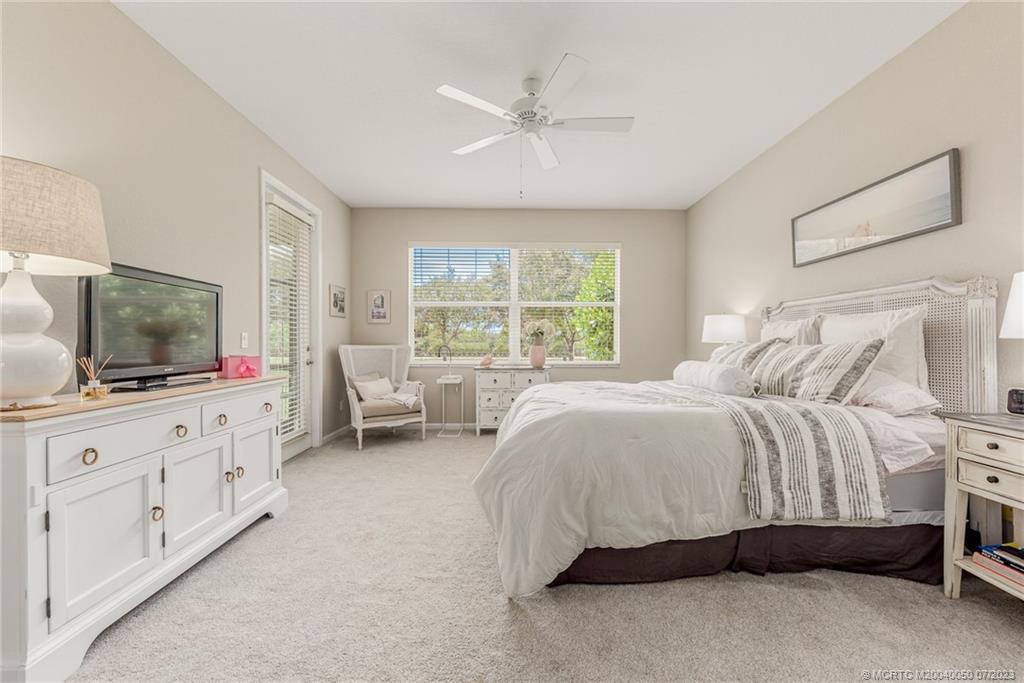2185 Northwest Dalea Way Stuart, FL 34994 - Photo 18 of 55 a spacious bedroom with a bed and a flat screen tv on dresser
