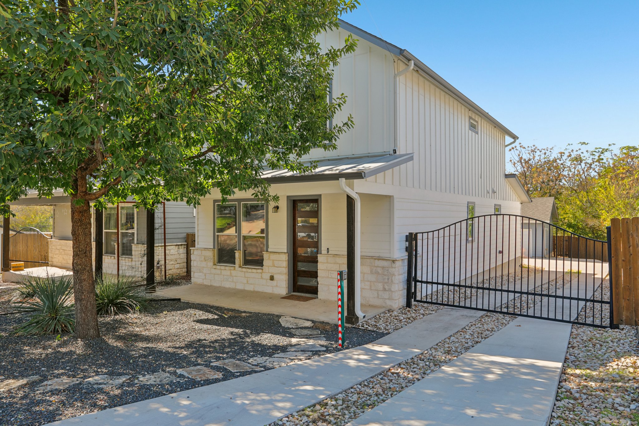 View of front facade with a gate, stone siding, and board and batten siding