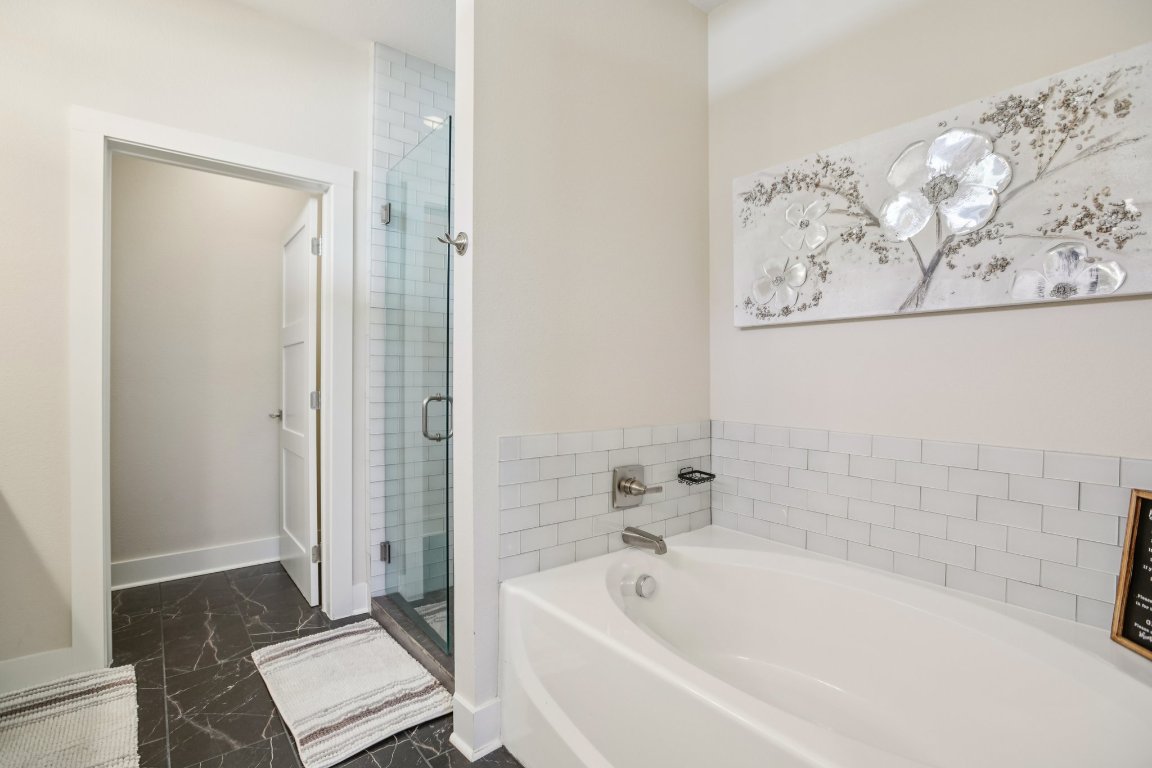 1206 Deloney Street, Unit B Austin, TX 78721 - Photo 14 of 39 Bathroom featuring dark marble finish floors, a garden tub, and a shower stall