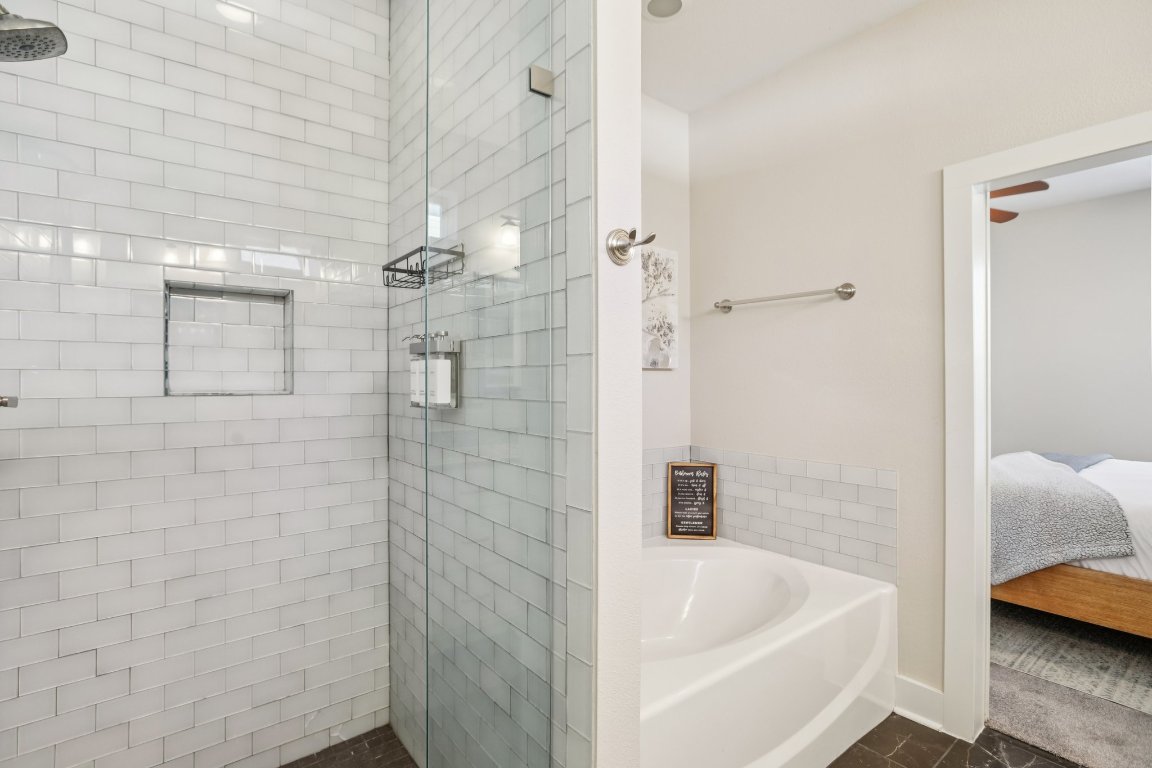 1206 Deloney Street, Unit B Austin, TX 78721 - Photo 16 of 39 Ensuite bathroom featuring a bath, a stall shower, and dark tile patterned floors