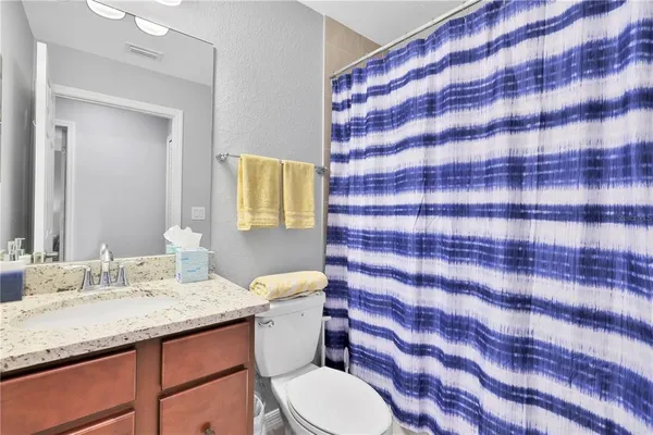 a bathroom with a granite countertop toilet sink and mirror