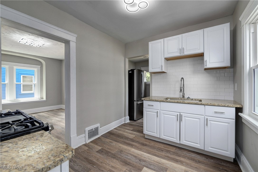 896 Selwyn Road Cleveland Heights, OH 44112 - Photo 8 of 23 Kitchen featuring white cabinetry, decorative backsplash, freestanding refrigerator, light stone counters, and dark wood-style floors