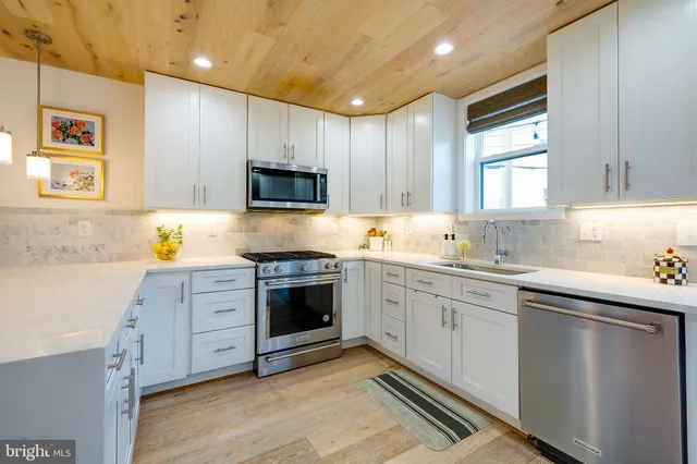 a kitchen with granite countertop a sink cabinets stainless steel appliances and a window