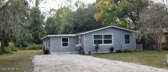 a view of a house with a yard and large trees