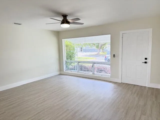a view of an empty room with wooden floor and a window