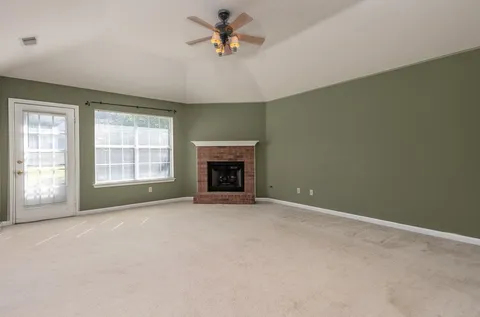 an empty room with windows and fireplace