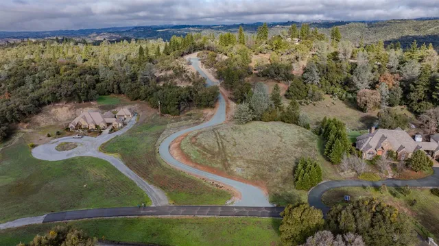 an aerial view of a houses with a yard and lake view