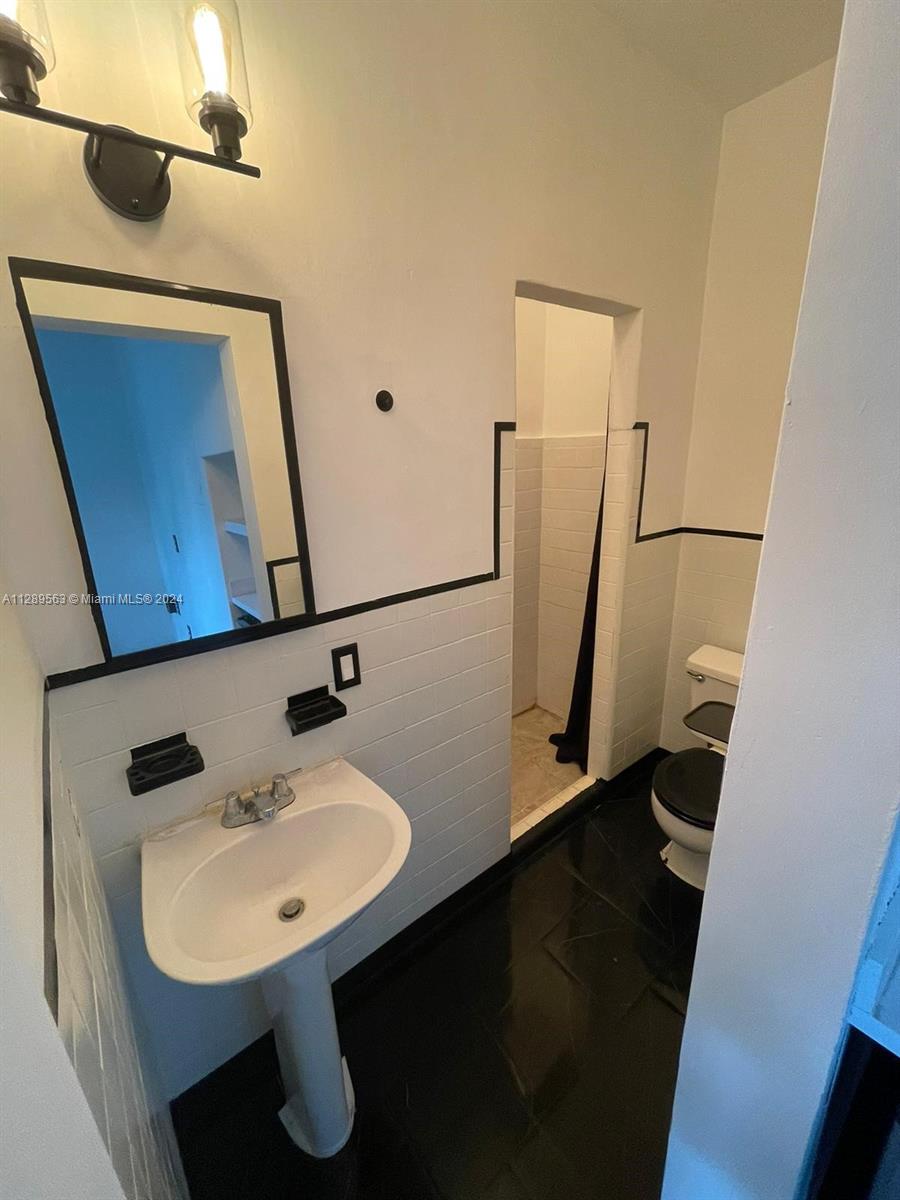 1455 Michigan Avenue, Unit 7 Miami Beach, FL 33139 - Photo 9 of 12 a bathroom with a sink a mirror and shower