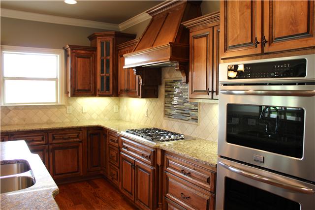Kitchen features all custom cabinets, stainless steel appliances, granite counter tops, and a tile and glass backsplash.