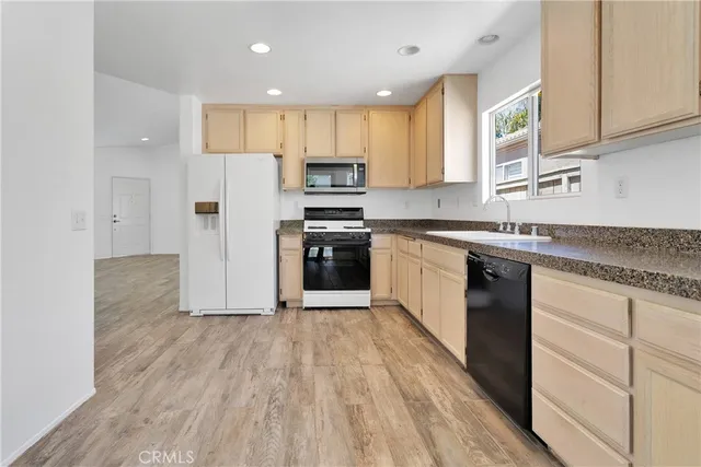 a kitchen with stainless steel appliances granite countertop a stove top oven a sink and a refrigerator