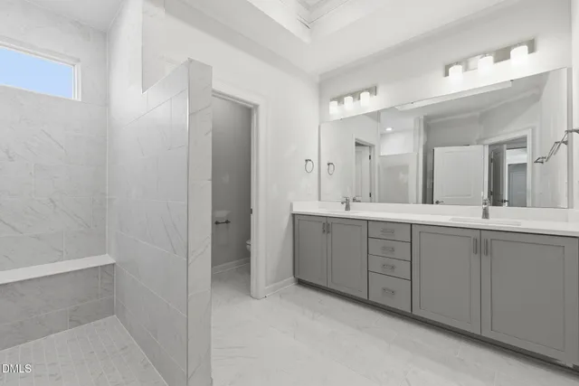 a spacious bathroom with a double vanity sink a mirror and a shower