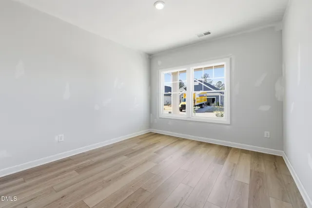 an empty room with wooden floor and window