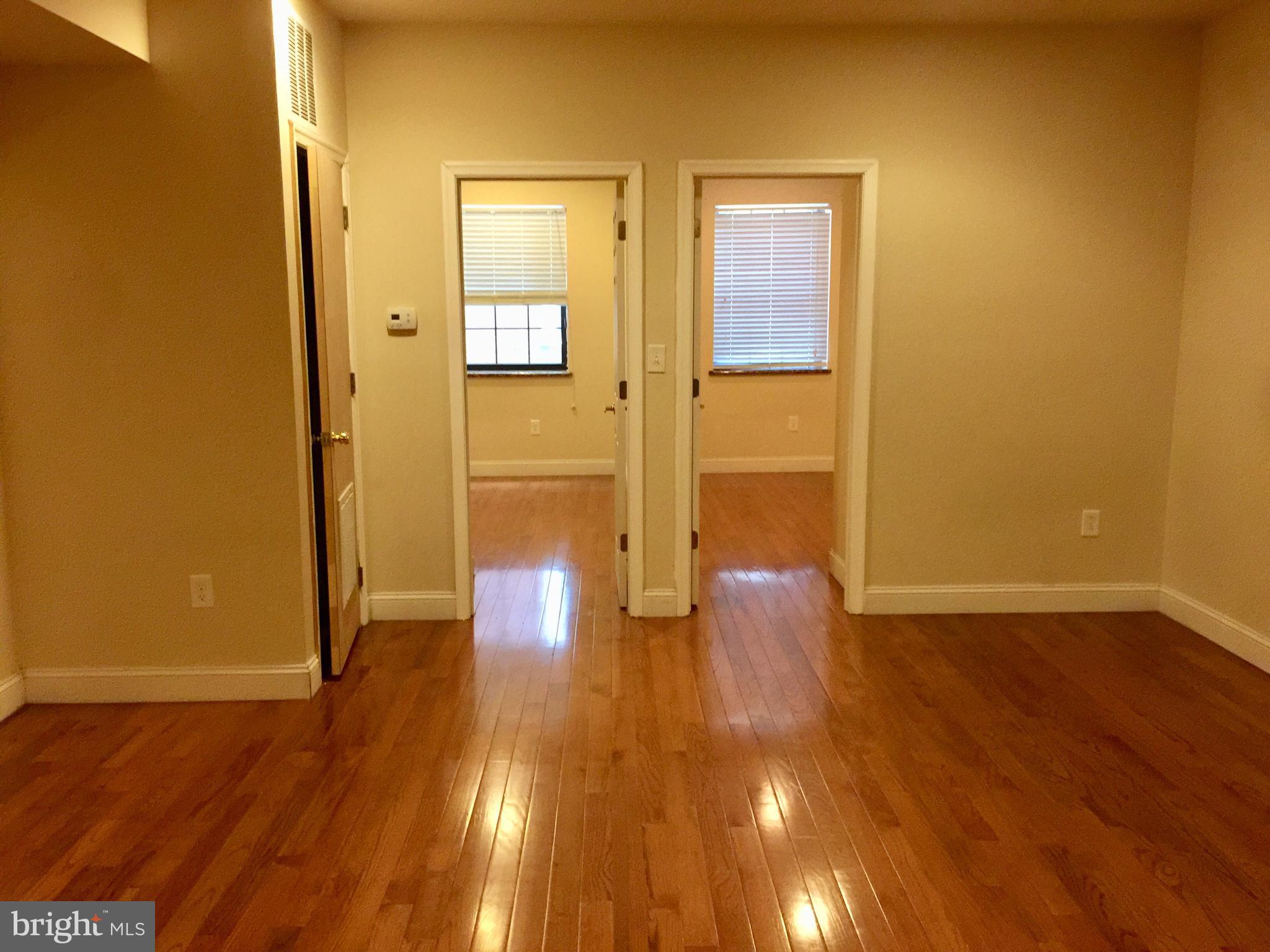 1241 Vine Street, Unit 2R Philadelphia, PA 19107 - Photo 4 of 7 a view of an empty room with wooden floor and a window