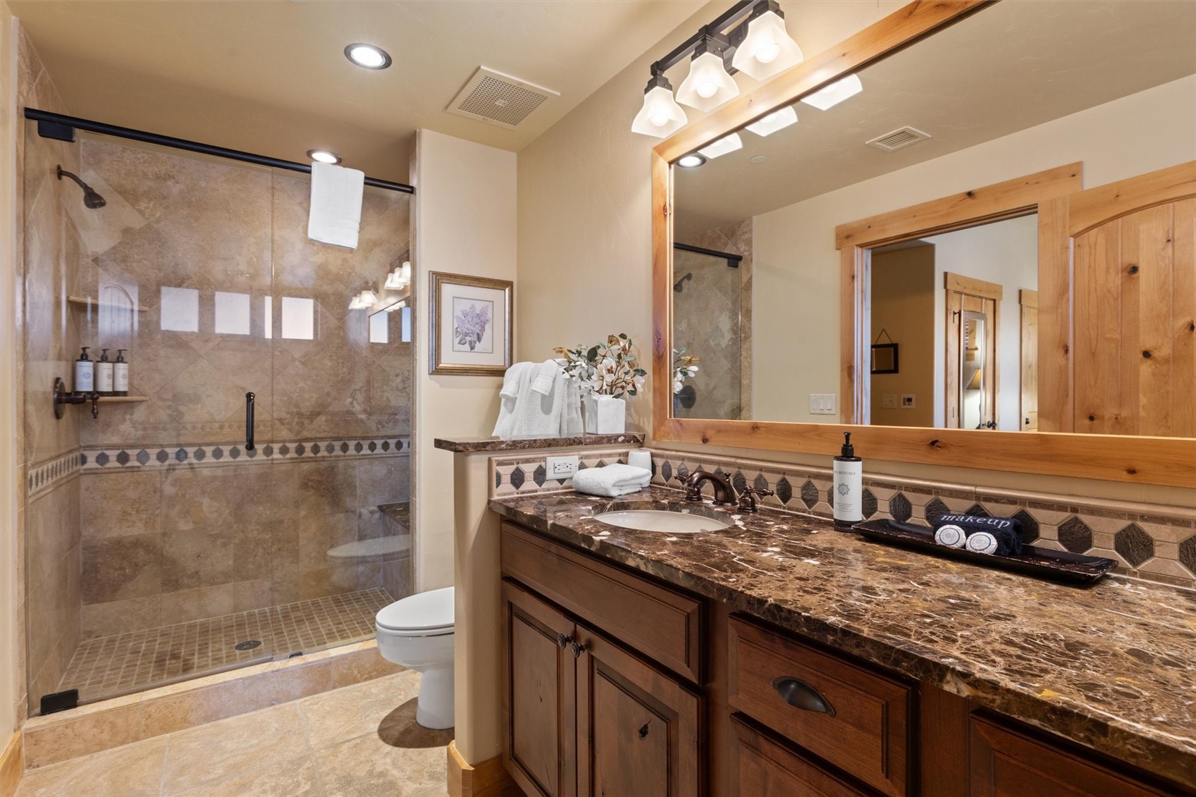 1750 Medicine Springs Road, Unit 6105 Steamboat Springs, CO 80487 - Photo 20 of 43 a bathroom with a granite countertop sink a toilet a mirror and shower
