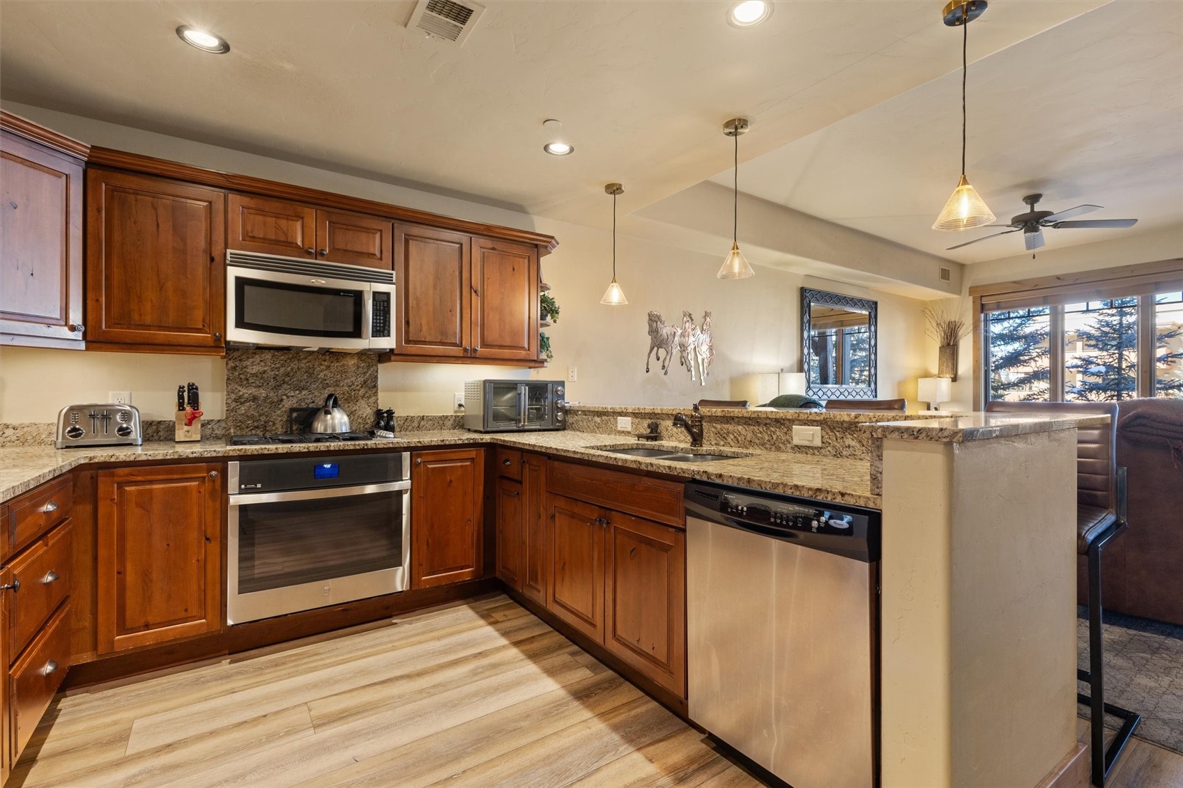 1750 Medicine Springs Road, Unit 6105 Steamboat Springs, CO 80487 - Photo 8 of 43 a kitchen with stainless steel appliances granite countertop a stove a sink dishwasher a refrigerator and a microwave oven with wooden floor