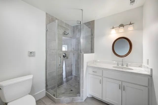 a bathroom with a toilet sink vanity granite and shower