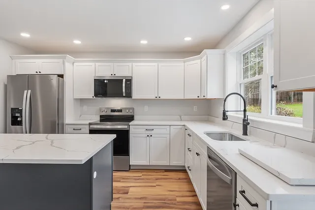 a kitchen with a sink white cabinets and stainless steel appliances