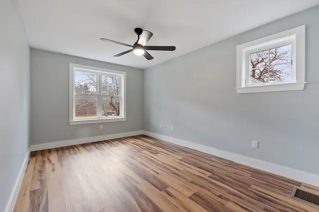 a view of empty room with wooden floor and fan