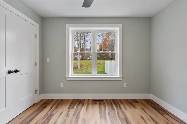 a view of an empty room with wooden floor and a window
