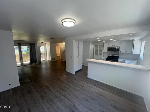 a kitchen with stainless steel appliances granite countertop a stove top oven a sink dishwasher and a refrigerator with wooden floor