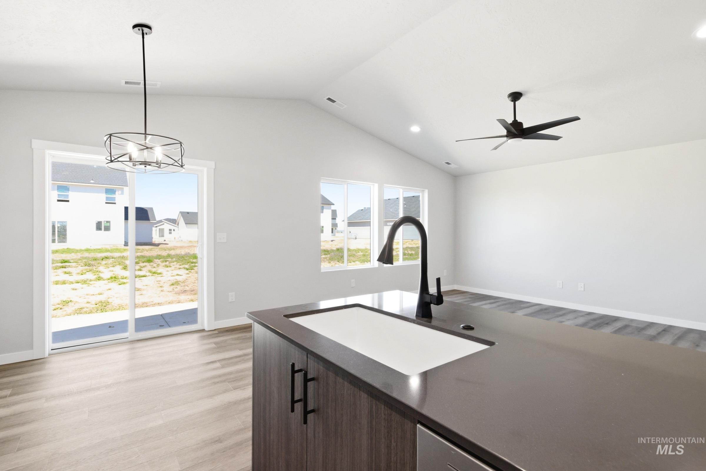 12805 Decatur Street Nampa, ID 83651 - Photo 9 of 20 Kitchen island with an undermount sink and matte black faucet, featuring a dark countertop and wood-finish cabinetry
