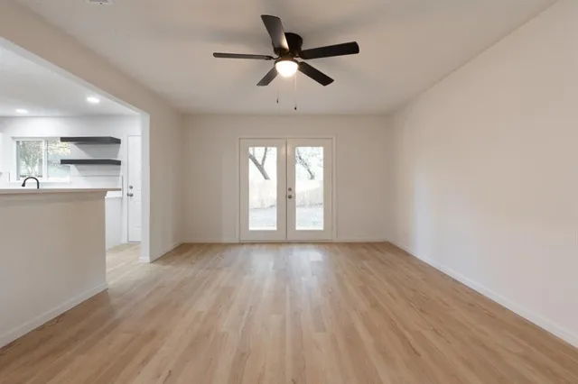 a view of an empty room with a window and wooden floor