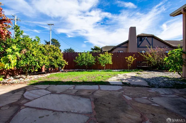 a front view of a house with a yard and large trees