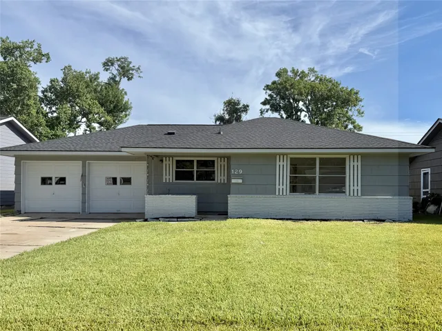 a front view of house with yard and trees in the background
