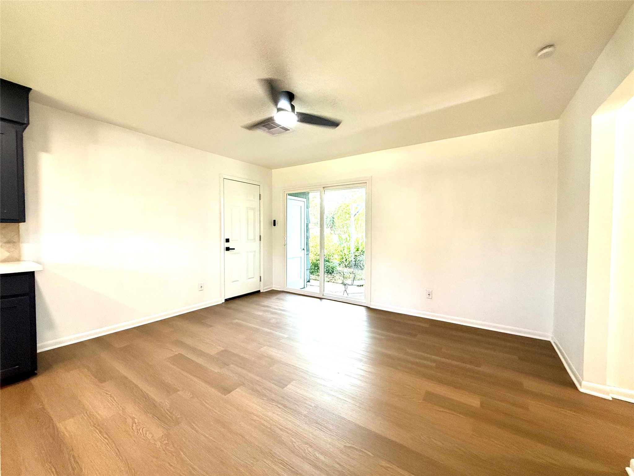 129 Chestnut Street Lake Jackson, TX 77566 - Photo 4 of 20 This bright, open living space features fresh white walls, wood flooring, a ceiling fan, and a sliding glass door leading to a garden area. Ideal for natural light and easy indoor-outdoor access.