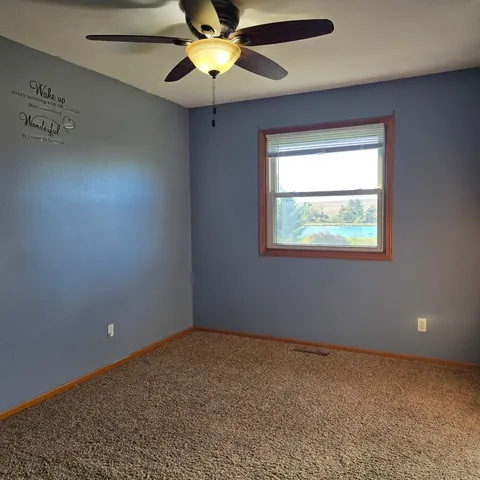 an empty room with a window and a fan