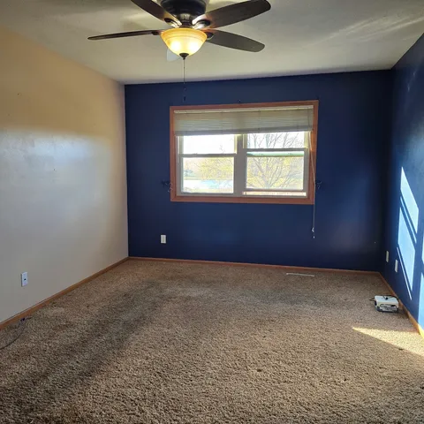 an empty room with a window and a ceiling fan