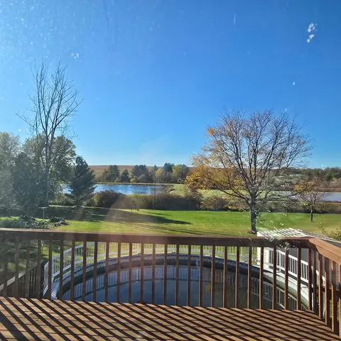 a view of wooden deck and lake with a house in background