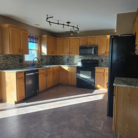 a kitchen with stainless steel appliances granite countertop a stove a sink and a refrigerator